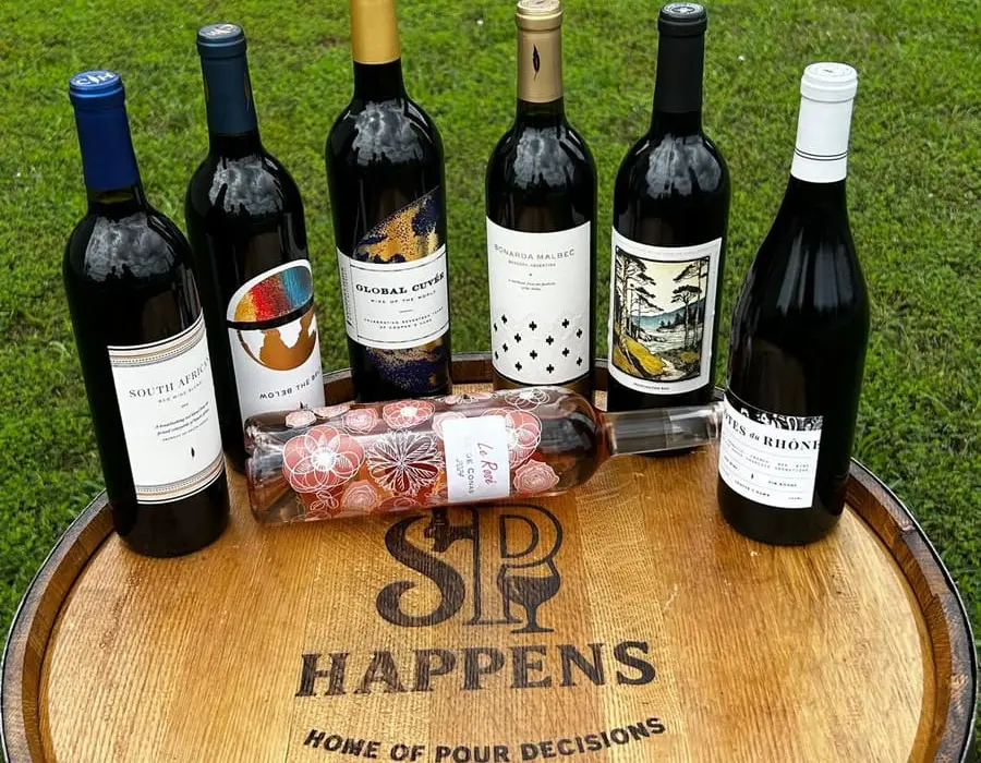 Wine bottles arranged on a Sip Happens branded barrel outdoors